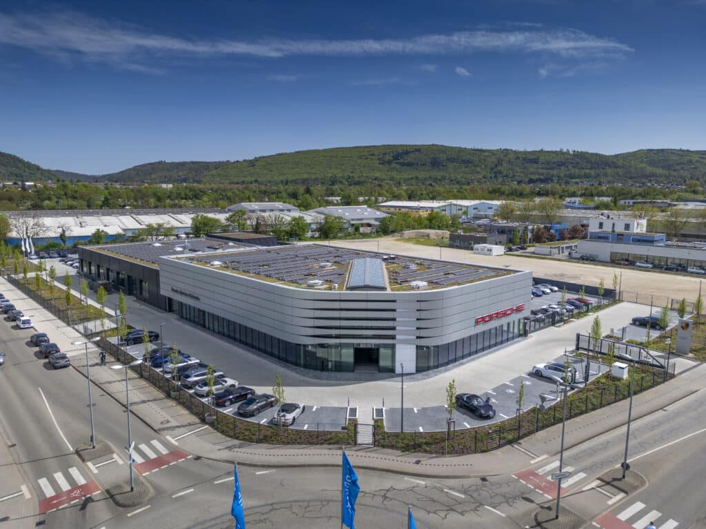 Luftaufnahme des Porsche Zentrums Karlsruhe mit begrüntem Dach, umliegenden Straßen und angrenzendem Gewerbegebiet.