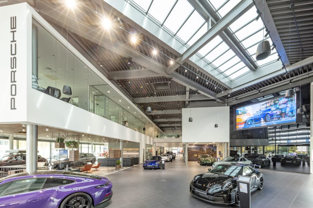 Innenraum des Porsche Zentrums Karlsruhe mit modernen Ausstellungsflächen, Glasbüros und präsentierten Porsche-Modellen.