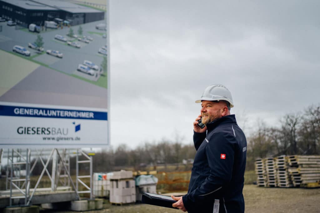 Bauleiter mit Bauhelm telefonierend auf einer Baustelle