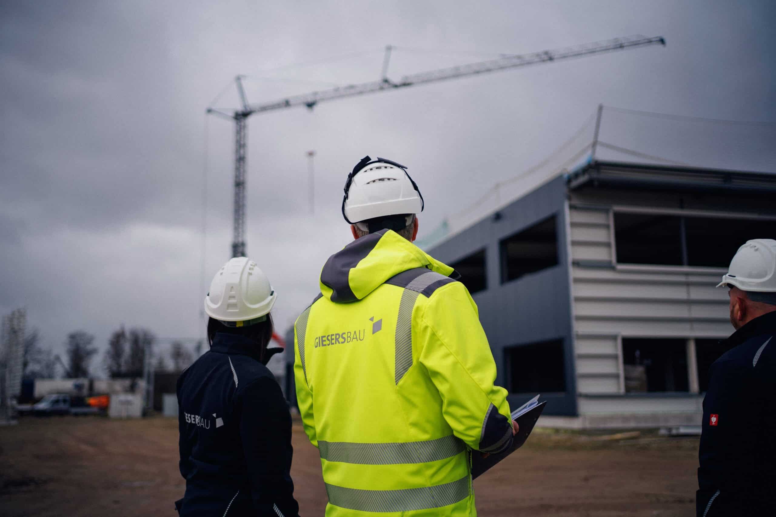 Zwei Mitarbeitende von Giesers Bau GmbH auf der Baustelle mit dem Rücken zur Kamera