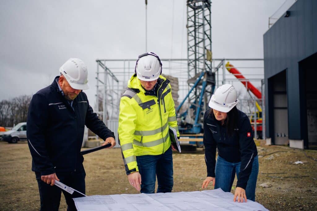 Mitarbeitende von Giesers Stahlbau GmbH auf einer Baustelle beim Ansehen von Plänen