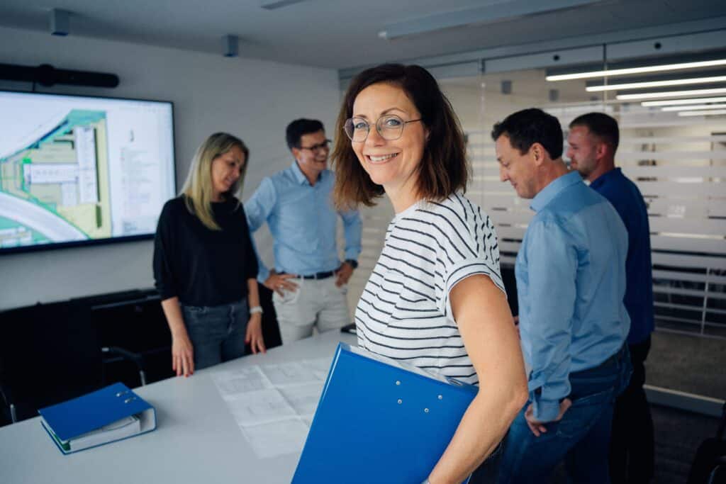 Mitarbeitende von Giesers Stahlbau GmbH stehen in einem Konferenzraum und schauen sich Pläne an