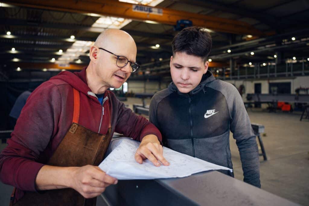 Zwei Mitarbeitende aus der Werkstatt bei Giesers Stahlbau GmbH beim analysieren der Pläne