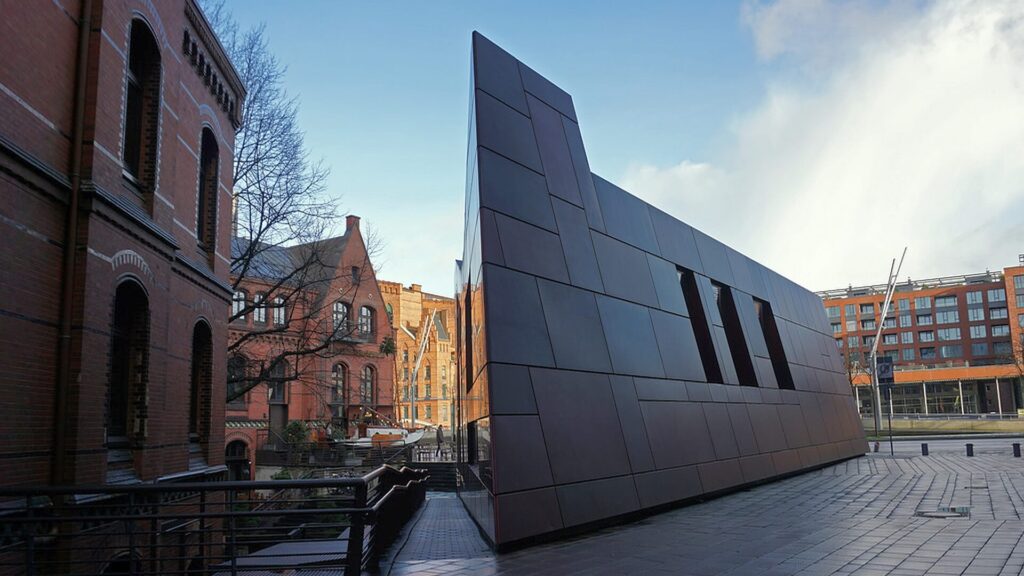 Moderner InfoPavillon Überseequartier Hamburg mit Metallfassade zwischen historischen Backsteingebäuden